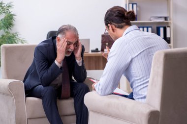 Yaşlı adam genç erkek doktor psikologunu ziyaret ediyor.