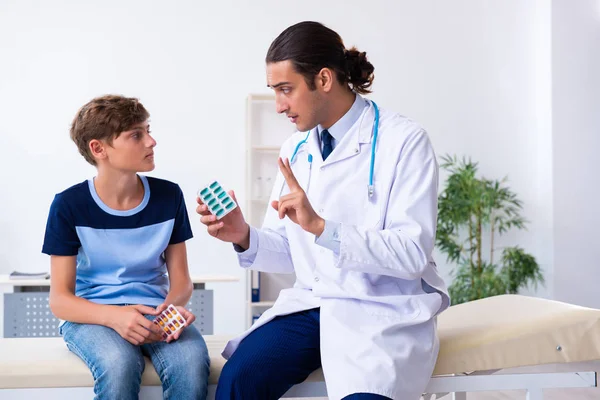 Jovem médico examinando menino na clínica — Fotografia de Stock