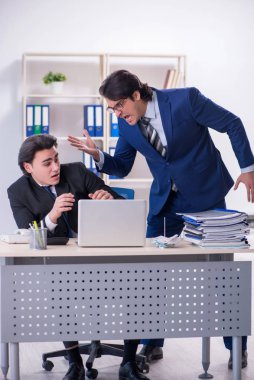 Patron ve erkek asistanı ofiste çalışıyor.