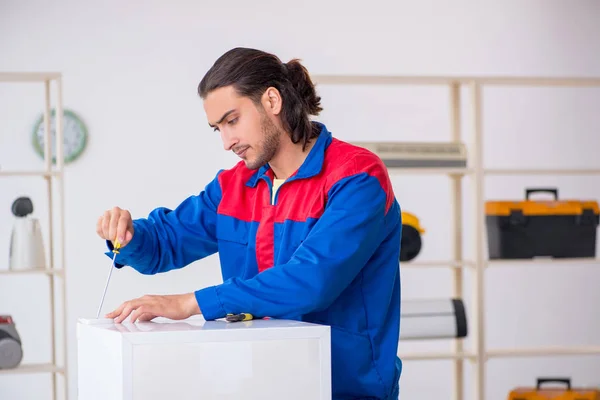 Joven contratista reparando refrigerador en taller — Foto de Stock
