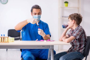 Genç çocuk hastanede doktoru ziyaret ediyor.