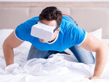 Yatakta sanal gerçeklik başlığı takan genç bir adam.