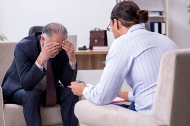 Yaşlı adam genç erkek doktor psikologunu ziyaret ediyor.