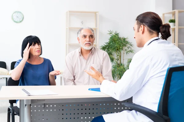 Pareja mayor visitando joven médico masculino — Foto de Stock