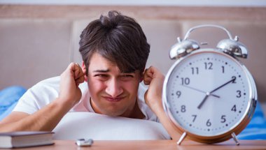 Yataktaki adam alarm yüzünden uykusuzluk çekiyor.