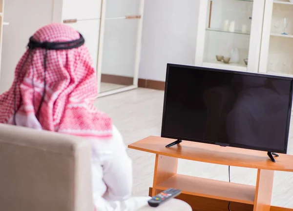 Arab businessman watching tv at home