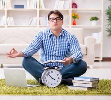 Genç yakışıklı adam evde yerde oturuyor.