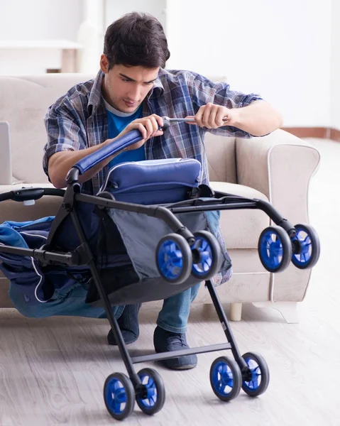 Young father assembling baby pram at home — Stock Photo, Image