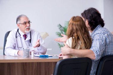 Genç çift yaşlı erkek doktoru ziyaret ediyor.
