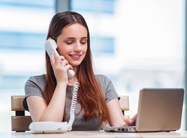 Genç bayan ofiste telefonla konuşuyor.