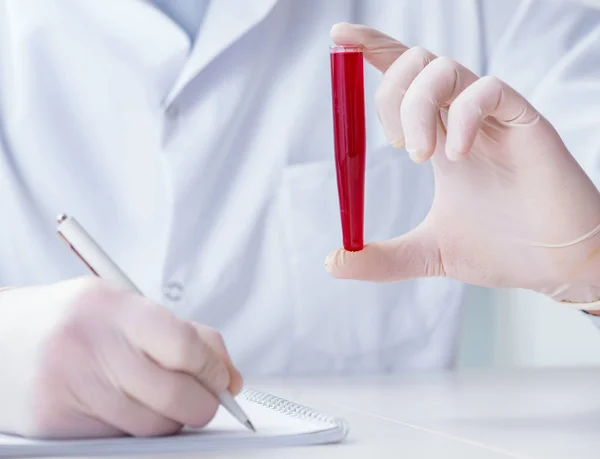 Médico joven en el laboratorio con tubo rojo — Foto de Stock