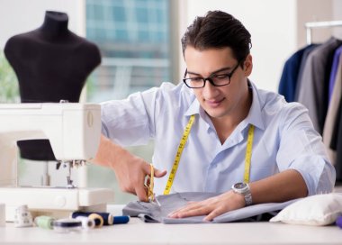 Genç terzi yeni elbiseler üzerinde çalışıyor.