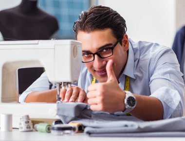 Genç terzi yeni elbiseler üzerinde çalışıyor.