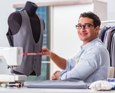 Genç terzi yeni elbiseler üzerinde çalışıyor.