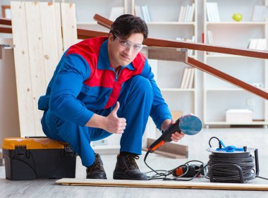 Genç marangoz ahşap kalaslarla çalışıyor.