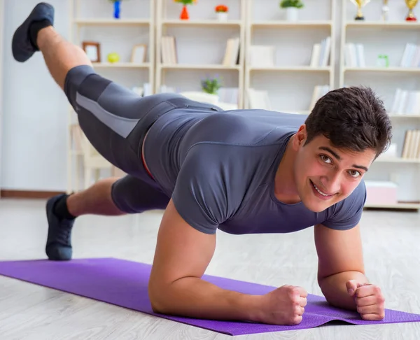 Joven haciendo ejercicio en casa en deportes y estilo de vida saludable con — Foto de Stock