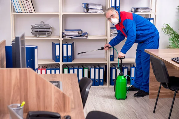 Velho empreiteiro profissional fazendo controle de pragas no escritório — Fotografia de Stock