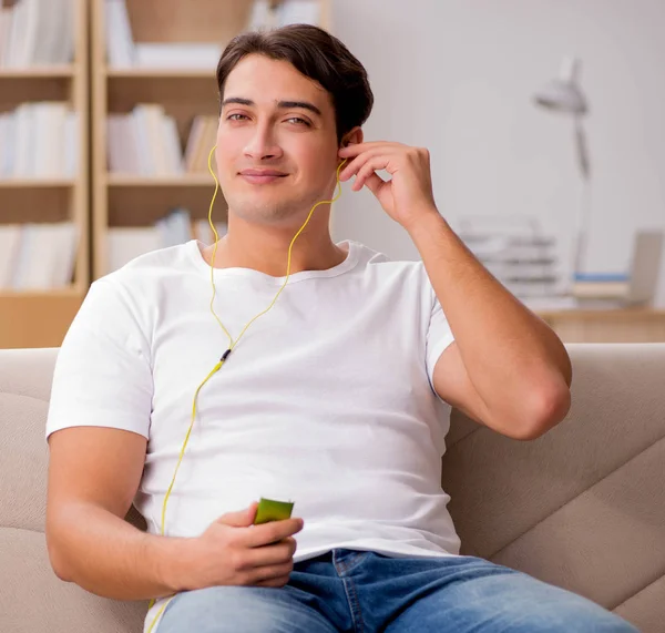 Hombre escuchando música sentado en el sofá —  Fotos de Stock