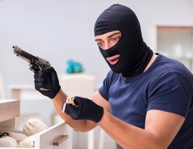 Soyguncu kar maskesi takıp değerli şeyler çalıyor.