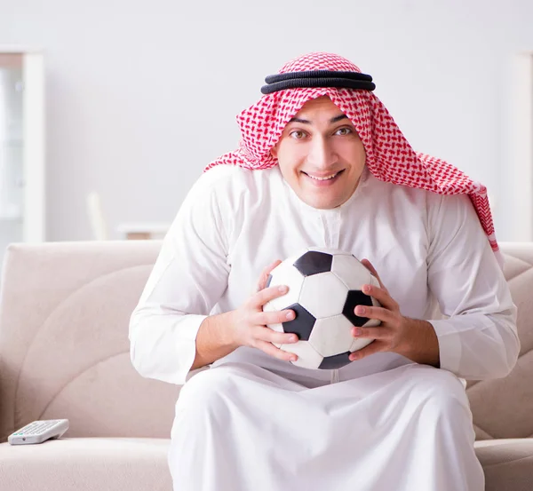 Hombre árabe joven viendo fútbol sentado en el sofá — Foto de Stock