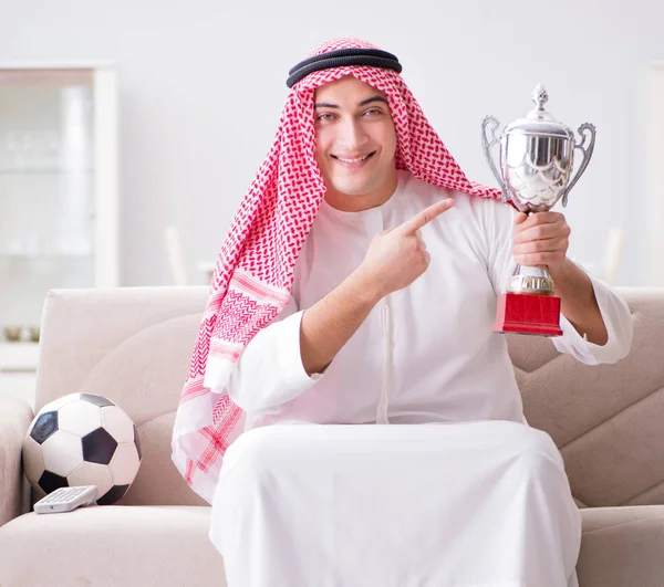 Genç Arap adam kanepede oturmuş futbol seyrediyor. — Stok fotoğraf