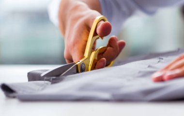 Genç terzi yeni elbiseler üzerinde çalışıyor.