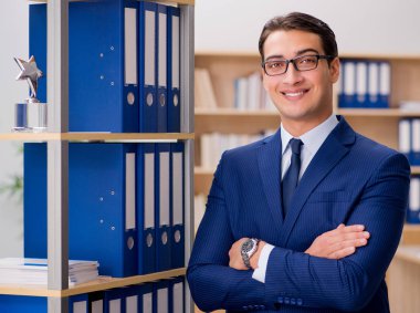 Yakışıklı işadamı raf yanında ayakta