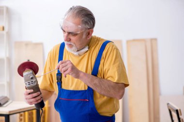 Yaşlı erkek marangoz atölyede çalışıyor.