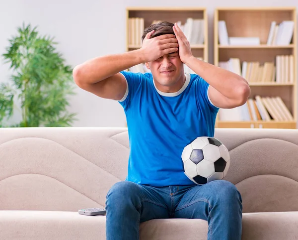 Hombre viendo fútbol en casa sentado en el sofá — Foto de Stock