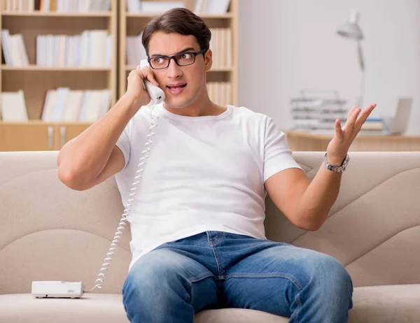 Giovane uomo che parla al telefono sdraiato sul divano — Foto Stock