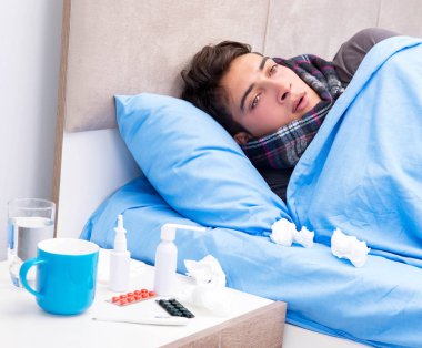 Grip olmuş hasta adam yatakta yatıyor.