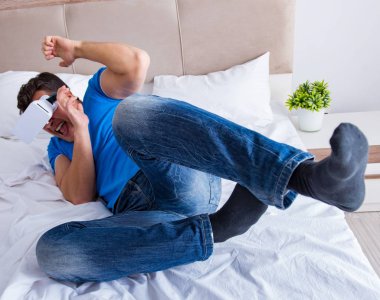 Yatakta sanal gerçeklik başlığı takan genç bir adam.