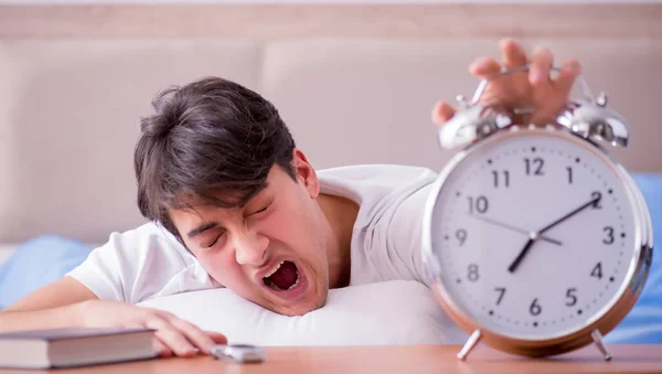 Мужчина в постели расстроен страданием от бессонницы с будильником — стоковое фото