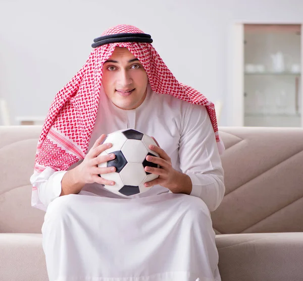 Hombre árabe joven viendo fútbol sentado en el sofá — Foto de Stock