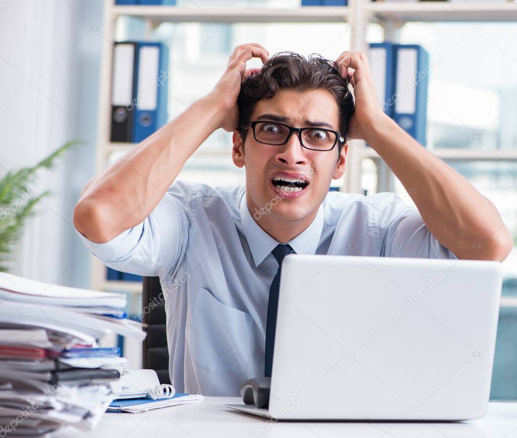 Young businessman under pressure in office to deliver tasks