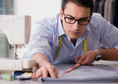 Genç terzi yeni elbiseler üzerinde çalışıyor.