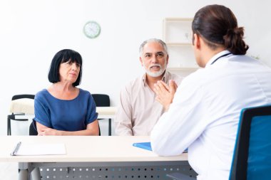 Yaşlı çift genç erkek doktoru ziyaret ediyor.