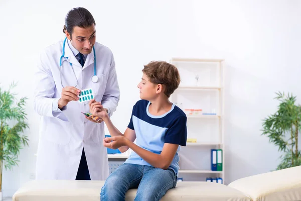 Jonge mannelijke arts onderzoeken jongen in de kliniek — Stockfoto