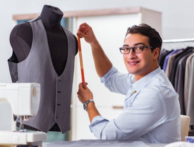 Genç terzi yeni elbiseler üzerinde çalışıyor.