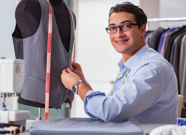 Genç terzi yeni elbiseler üzerinde çalışıyor.