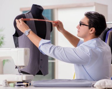 Genç terzi yeni elbiseler üzerinde çalışıyor.