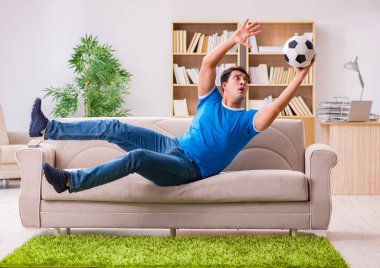 Evdeki kanepede oturup futbol izleyen bir adam.