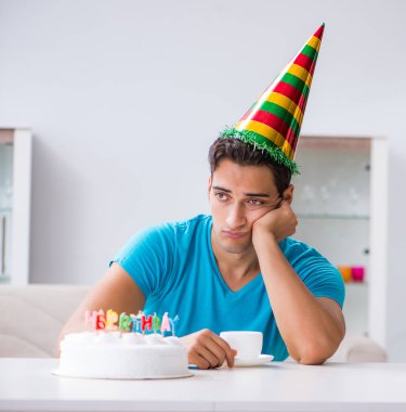 Genç adam doğum gününü evde yalnız kutluyor.