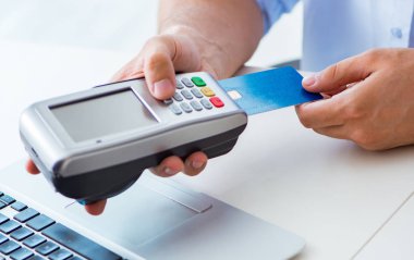 POS terminali ile kredi kartı işlemi yapan adam