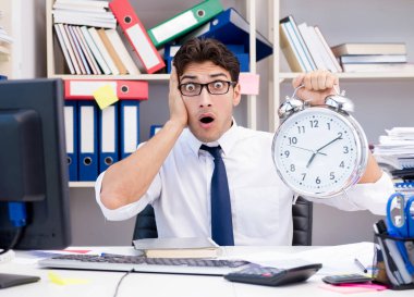 Ofiste kitap ve kağıtlarla çalışan bir işadamı.