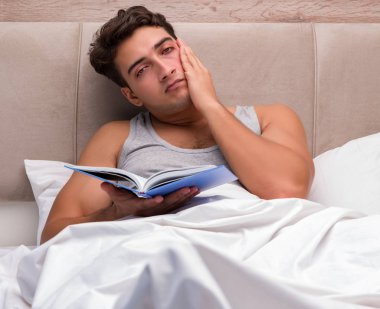Adam yatakta kitap okumak