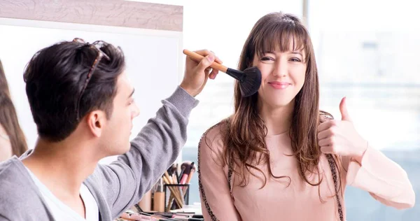 Uomo che fa il make-up per la donna carina nel salone di bellezza — Foto Stock