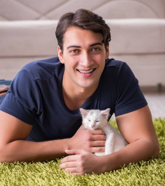 Yakışıklı delikanlı beyaz yavru kedi ile oynarken
