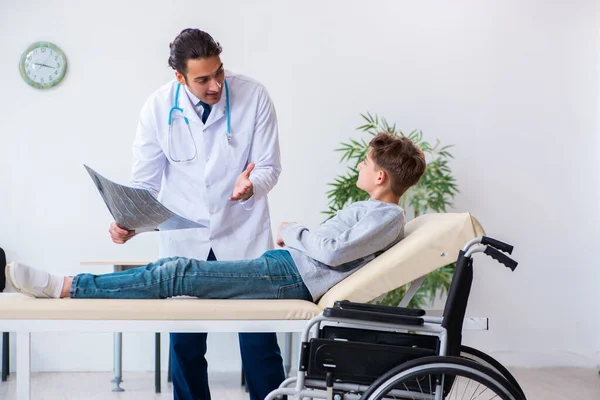 Молодой врач-педиатр и мальчик в инвалидной коляске — стоковое фото