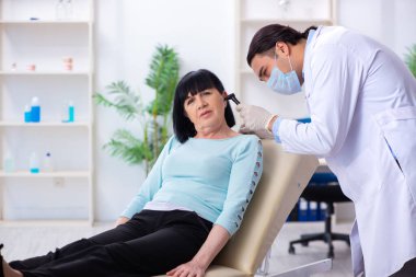 Yaşlı kadın genç doktor laringologu ziyaret ediyor.